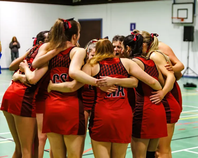 A group of people in the same red strip are huddling together.